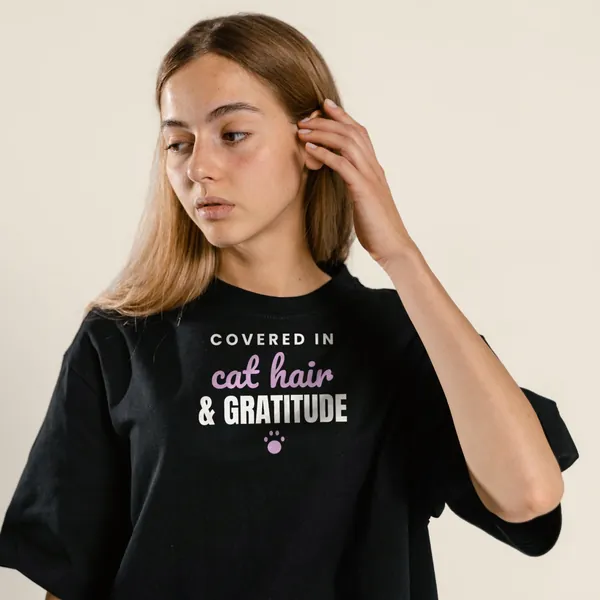 Model wearing a black "Covered in Cat Hair and Gratitude" tee with the light-ink version of the design